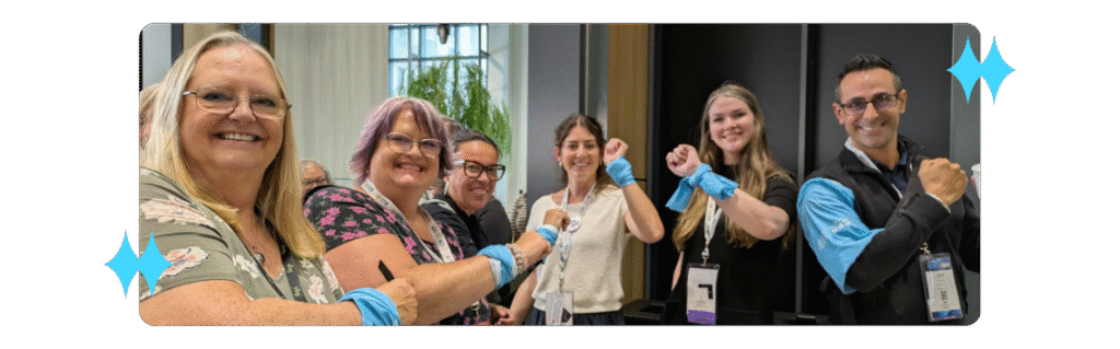IGNITE 2025 attendees and staff smiling and holding up their colourful armbands