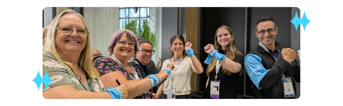 IGNITE 2025 attendees and staff smiling and holding up their colourful armbands
